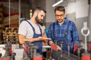 Two manufacturing workers talking over a machine