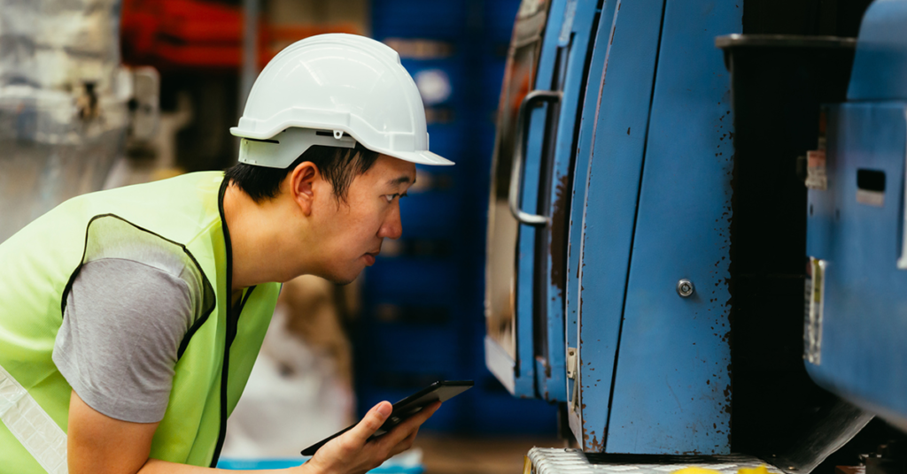 factory worker examining a machine