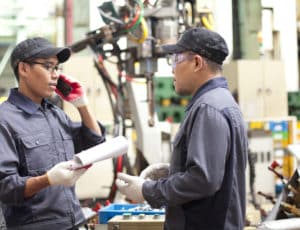 Two technician in a factory talking how repair a robot machine