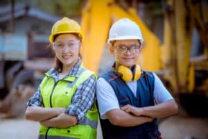 Portrait Industrial engineer and worker woman wearing safety uniform and safe helmet posing smile for work and control machines with industry factory background.