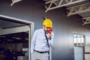 Angrydirector in shirt and tie and with helmet on head shouting while having unpleasant conversation