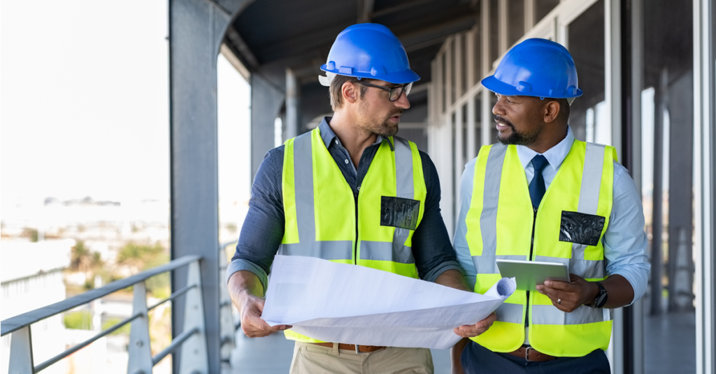 Two men wearing hardhats and talking